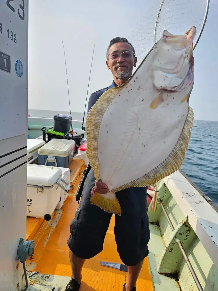 余市の海で釣り上げたヒラメを掲げるシェフ